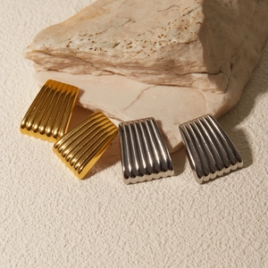 Detail showing polished gold and silver textured earrings on beige stone display
