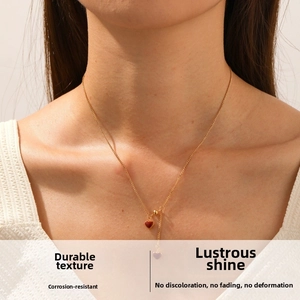 Close-up of golden chain necklace featuring a wine red heart pendant and elegant fringe tassels