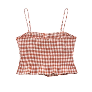 Detail of red and white gingham crop top featuring smocked fabric and ruffled hemline