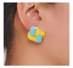 Detail showing a geometric yellow and blue drip oil stud earring worn on the ear