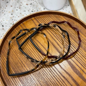 Close-up of wavy tortoiseshell acetate headbands displayed on a circular wooden tray