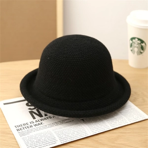 Macro view of black knit dome bucket hat with rolled edge texture on a magazine