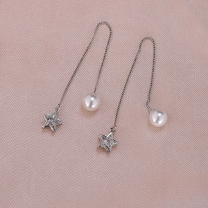 Detail of silver drop earrings with star pendant and pearl on purple silk background