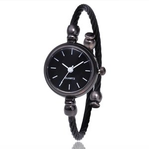 Close-up of black cable bangle watch featuring a minimalist quartz dial and rounded clasp