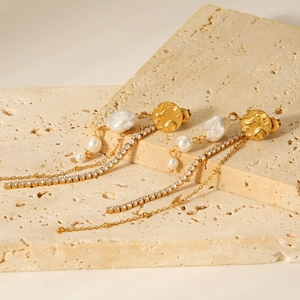 Baroque pearl earrings with zircon chains and golden texture studs on stone base