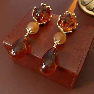 Detail of vintage amber droplet earrings with gold metal on a leather jewelry box