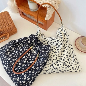 Détail du sac cabas en toile florale avec anses en cuir marron et étiquette tissée