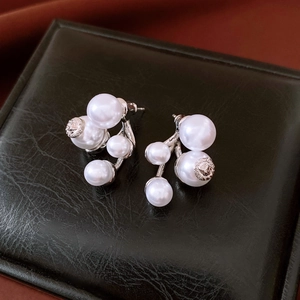 Detail of pearl earrings with Greek fret pattern and Medusa relief on leather surface