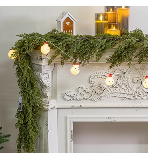 Close-up of artificial pine garland with snowman LED lights and battery box for Christmas