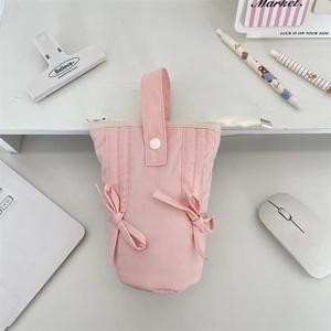 Pink canvas pen case with bow details and handle shown in a neat desktop office setting