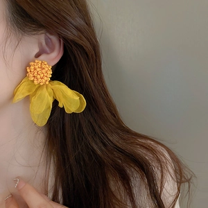 Fashionable oversized yellow mesh flower earrings with bead center worn by a model