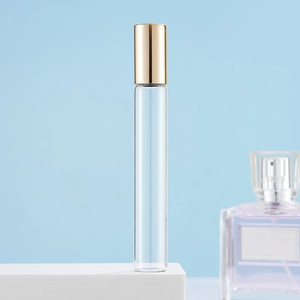 Clear glass roller bottle with golden cap on white stand against light blue background