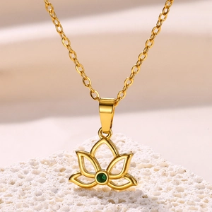 Detailed macro view of 18K gold lotus pendant with green zircon on textured stone base