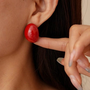 Close-up of a minimalist vintage red oval stud earring worn by a female model