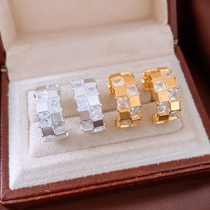 Vue macro de boucles d'oreilles en C dorées et argentées avec zircons carrés et boîte à bijoux