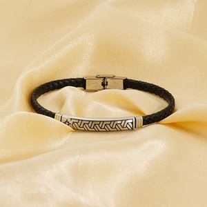 Minimalistisches Lederarmband mit Edelstahl-Charm auf glänzendem Seidenhintergrund