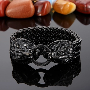 Macro detail of men's black stainless steel lion head bracelet on reflective base