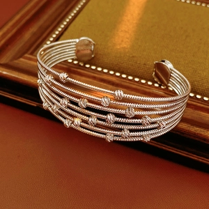 Macro d'un bracelet multicouche argenté à perles sur cadre vintage et cuir rouge