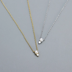 Detail of silver and gold chain necklaces featuring elegant pearls and sparkling zircons
