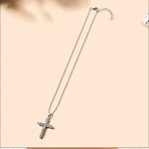Detailed close-up of a silver cross necklace with sparkling crystals and lobster clasp