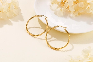 Detail of gold beaded hoop earrings featuring a unique textured ball chain design