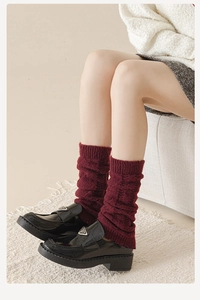 Gros plan de jambières en tricot rouge foncé avec texture côtelée et mocassins