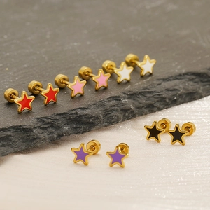 Macro detail of colorful star-shaped stud earrings in gold finish on elegant stone background