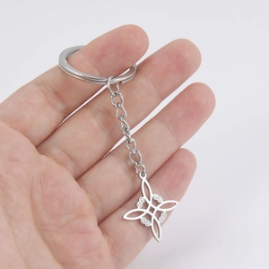 Macro shot of silver stainless steel witch's knot keychain held by hand for size context