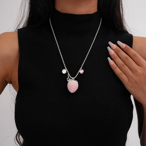 Detail of pink flocked strawberry pendant on a silver ball chain worn over black sweater