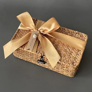 Detail of hand-woven seagrass gift basket with a champagne gold satin bow and pearl charm