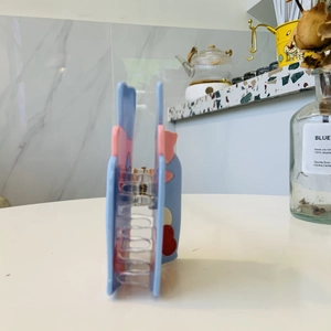 Detail view of light blue acrylic fishbowl hair claw with strawberry and heart patterns