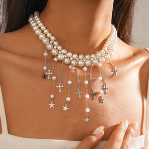 Détail du collier de perles double épaisseur avec pendentifs étoile et croix sur un mannequin
