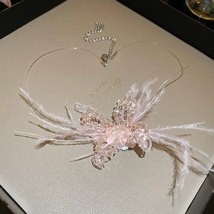 Detail of pink feather butterfly earrings with crystal beads on a beige texture tray