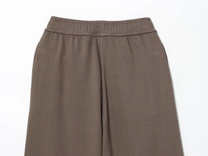 Detail of elastic waistband and knit fabric texture on brown casual trousers