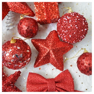 Detail of red glitter Christmas ornaments with gift boxes stars and beads on white background