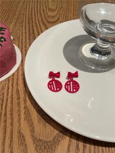 Detail of red festive bow earrings with Chinese Fu character pendant on a white plate