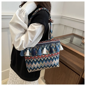 Ethnic canvas tote bag with bohemian wave patterns and tassels worn over the shoulder