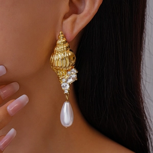 Detail of conch earrings with pearls and rhinestones on model with soft lighting