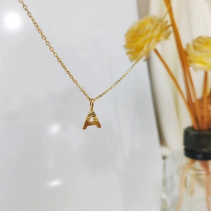 Detailed close-up of golden alphabet A pendant necklace with radial engraved texture