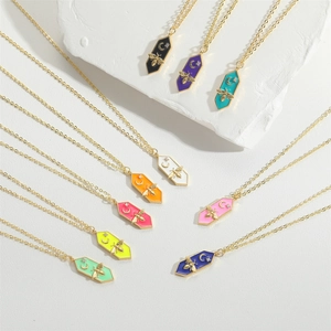Colorful enamel bee and moon pendants on gold chain necklaces displayed on white stone