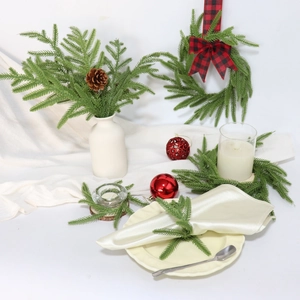 Close-up of Norfolk pine needles with red plaid ribbon and festive Christmas ornaments