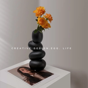 Minimalist matte black pebble-shaped ceramic vase featuring stacked egg design with roses