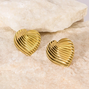 Polished gold heart-shaped earrings with textured leaf stripes on minimalist stone