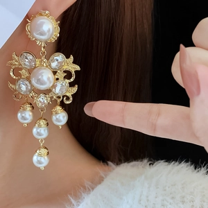 Close-up of vintage baroque gold earrings with pearls and crystals on female model