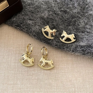18k gold plated rocking horse earrings set with hammered metal texture on elegant fabric