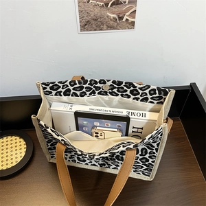 Leopard print canvas tote bag with brown leather handles showing large inner capacity