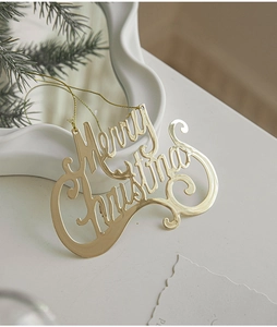 Close-up of golden Merry Christmas hanging ornament on a festive minimalist tabletop