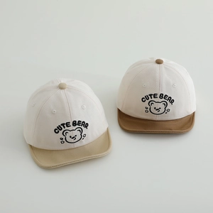 Detail of cute bear embroidery on soft-brim baby baseball caps in two neutral colorways