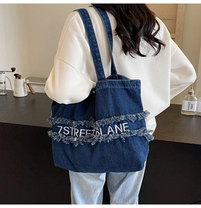 Gros plan d'un sac cabas en denim bleu avec broderie 7STREETLANE et détails effilochés