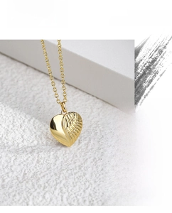Macro close-up of the heart-shaped wing pendant with detailed gold feather textures
